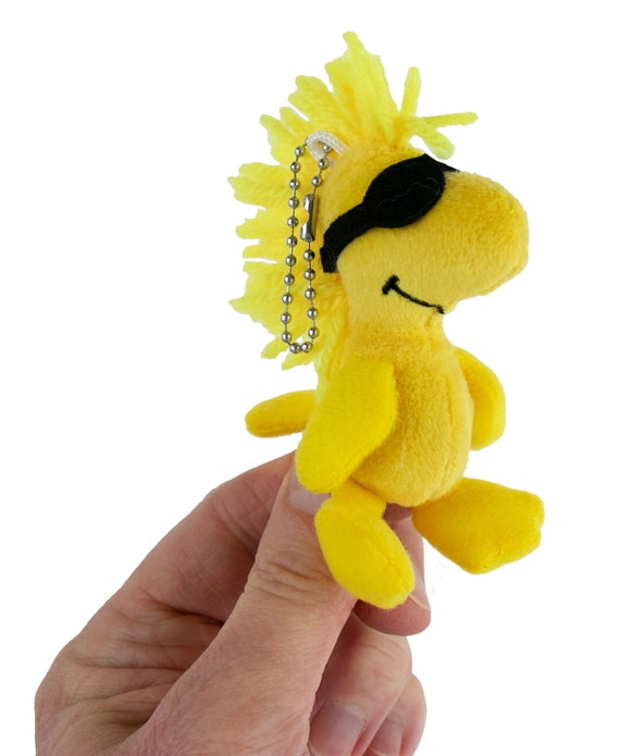 Yellow plush monkey keychain held by a hand on a white background