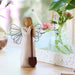 Decorative angel figurine with a shovel in a home setting with flowers and decor.