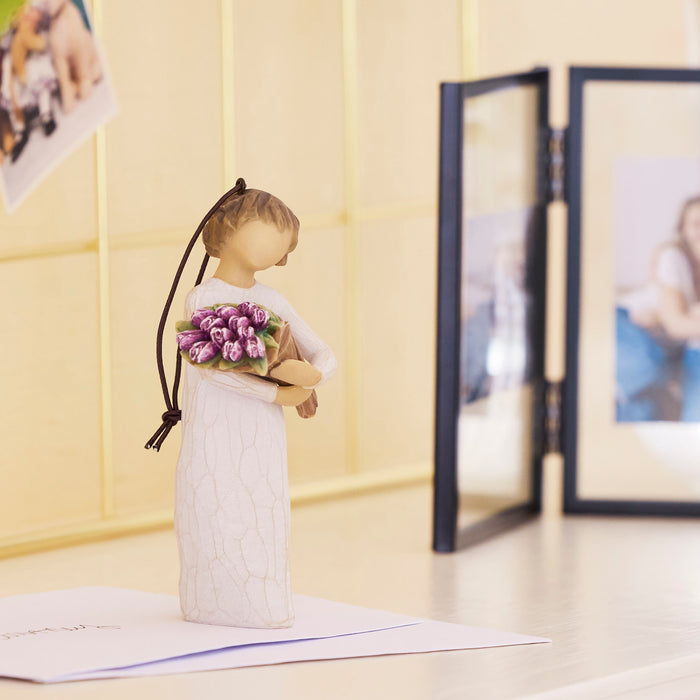 Decorative figurine of a girl holding flowers on a table with a light background