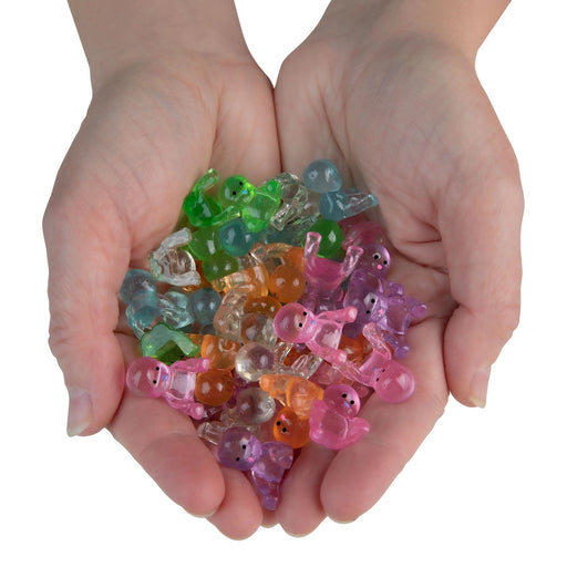 Colorful transparent animal-shaped beads held in hands against a white background