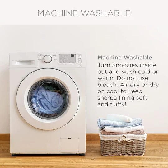 White washing machine with clothes inside, next to a basket of folded clothes on a wooden floor.