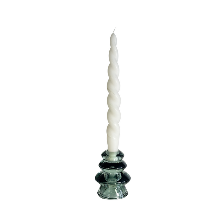 White spiral candle on a glass candlestick against a white background