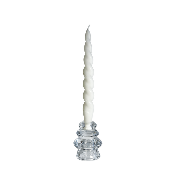 White spiral candle on a clear glass holder against a white background