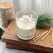 Glass of milk with a small snowman candle on a wooden surface