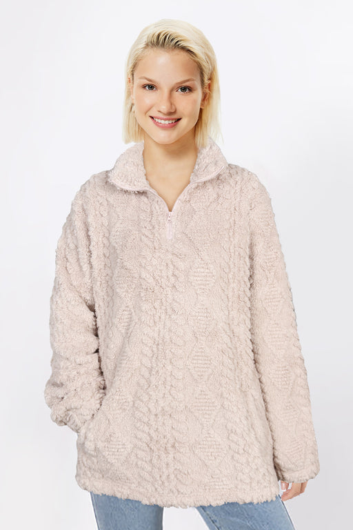 Woman wearing a beige fleece pullover against a white background