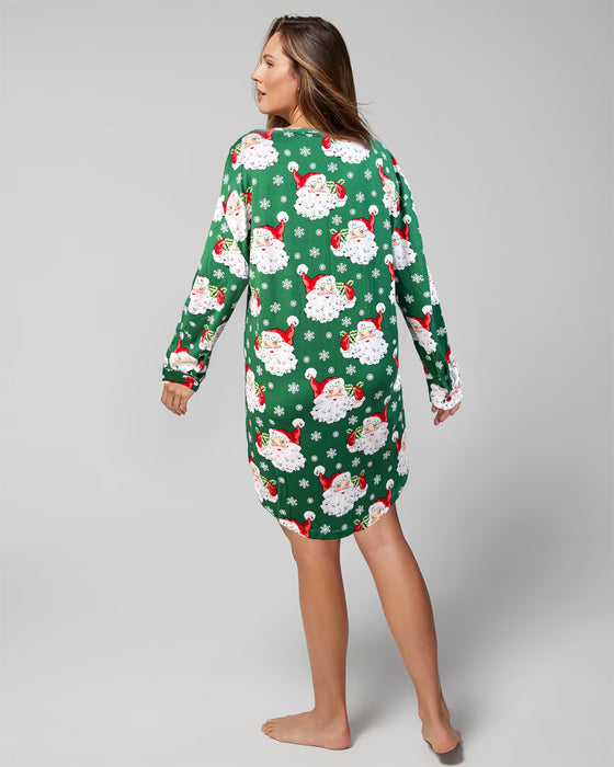 Woman wearing a green Christmas-themed nightshirt with Santa Claus pattern on a gray background