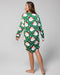 Woman wearing a green Christmas-themed nightshirt with Santa Claus pattern on a gray background