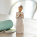 Decorative figurine of a woman holding a bird on a wooden surface with a blurred background
