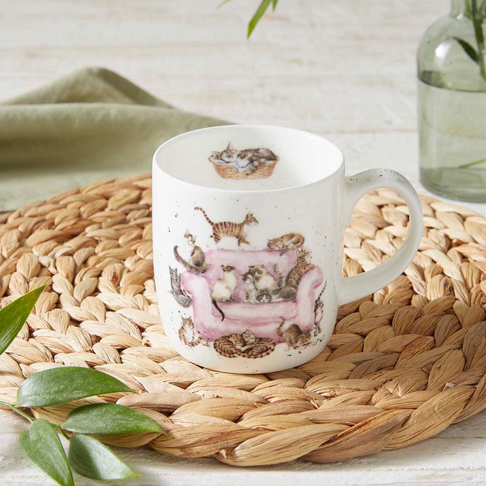 White mug with cat illustrations on a woven mat