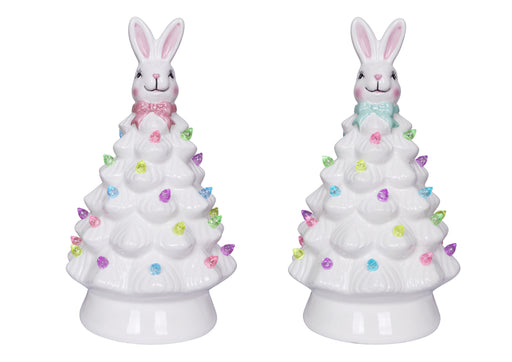 Two ceramic Christmas trees with bunny figures on top against a white background