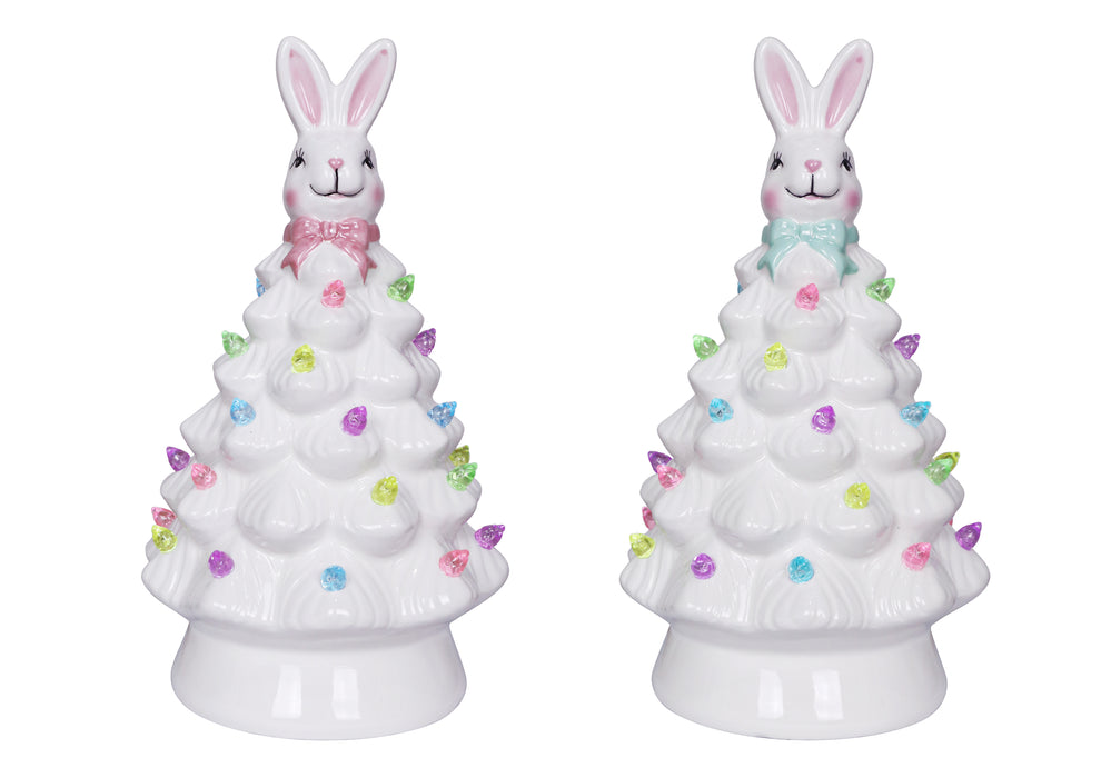 Two ceramic Christmas trees with bunny figures on top against a white background