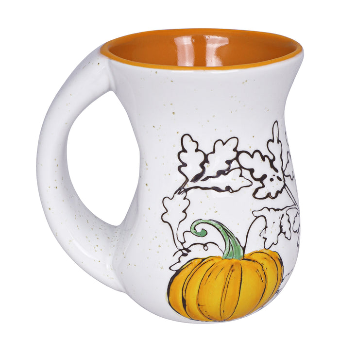 White mug with orange interior, pumpkin, and leaf design on a white background
