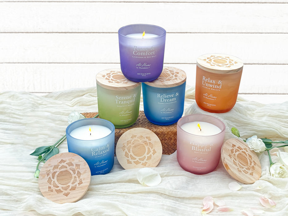 Collection of scented candles with wooden lids on a textured surface