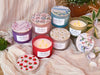 Assorted candles with decorative lids on a soft fabric background
