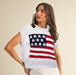 Woman wearing a white sleeveless top with an American flag design on a beige background