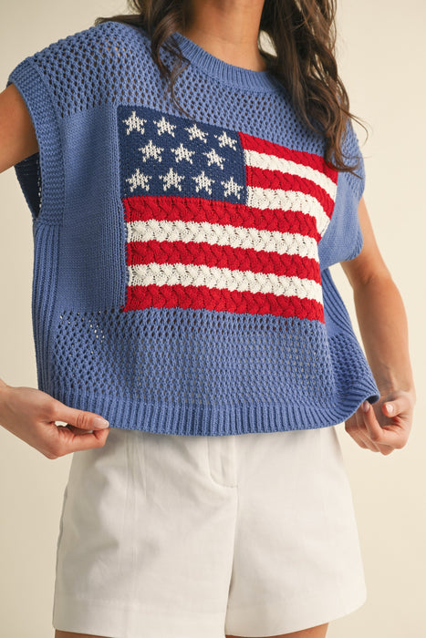 Person wearing a blue sleeveless sweater with an American flag design on a beige background