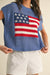 Person wearing a blue sleeveless sweater with an American flag design on a beige background