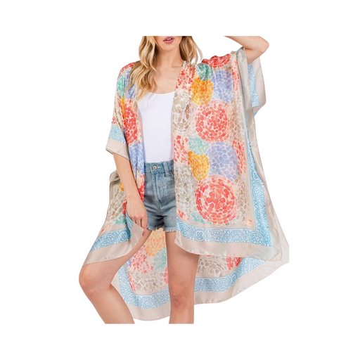 Woman wearing a colorful floral kimono over a white top and denim shorts on a white background