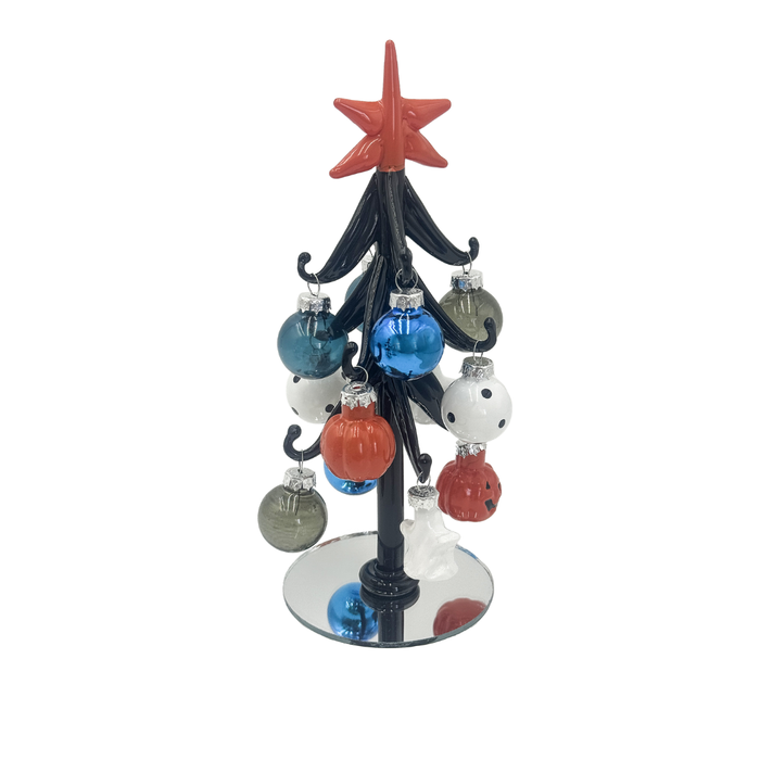 A miniature black Christmas tree ornament with a red star topper and hanging multicolor glass baubles on a mirrored base, isolated on a white background.