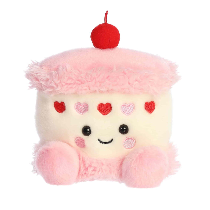 Plush toy shaped like a cupcake with pink frosting, red cherry, and heart decorations on a white background.