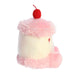 Plush toy resembling a cake with pink frosting and a red cherry on top against a white background