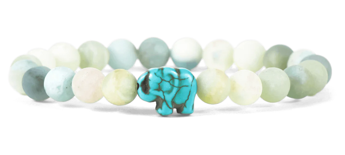 Bracelet with light-colored beads and a turquoise elephant charm on a white background