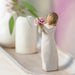 Decorative figurine of a woman holding flowers on a marble surface with a blurred background