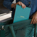 Person holding a teal notebook with 'Lifelines' branding, sitting on a green chair.