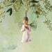 Angel figurine with butterfly wings hanging against a light green background with foliage.