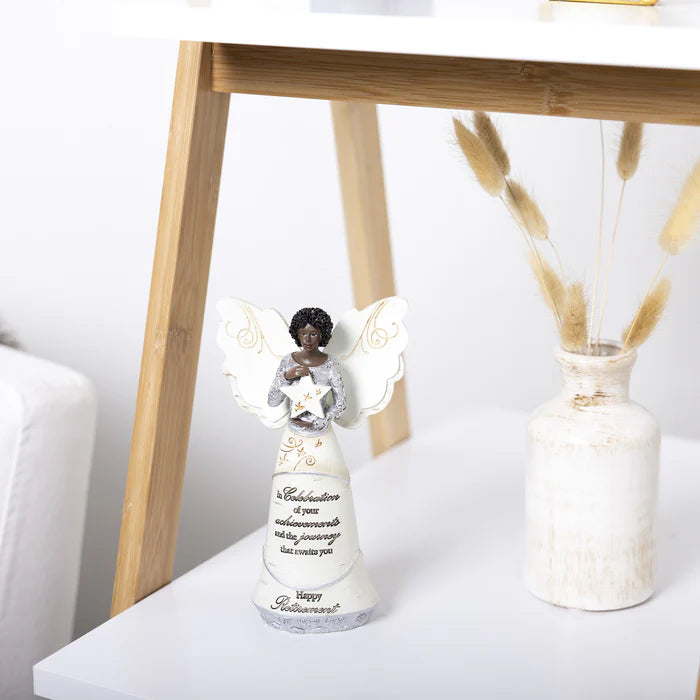 Decorative angel figurine on a white surface with a wooden stand and vase in the background.