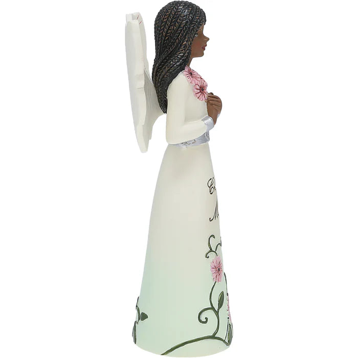 Statue of an angel with braided hair holding flowers, wearing a long white dress with floral patterns on a white background.