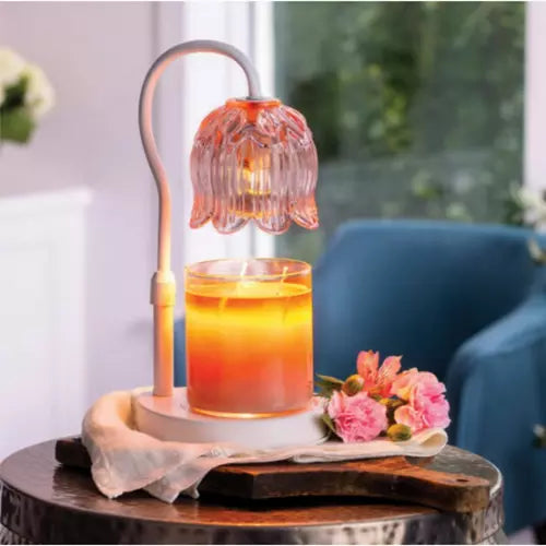 Decorative lamp with a glass of orange liquid on a wooden table.