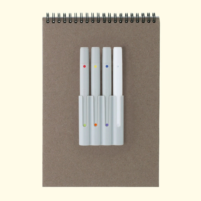 Set of four markers with colored dots on a brown notebook