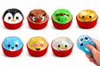 Eight small squishy toy containers arranged in a grid on a white background, each with a different cartoon face and glittery color. A human hand is shown squeezing one of the blue glittery toys in the bottom-right corner.