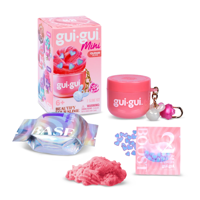 A pink beauty slime kit by gui-gui. Mihi Glow, shown with its retail box, a pink jar, a silver and blue iridescent foil packet labeled BASE, a pink packet labeled BOOST, a small pile of pink slime, and blue heart-shaped pieces on a white background.