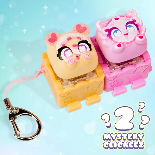 Two cute cartoon mouse-shaped clickers in pastel colors, one yellow with pink accents and one pink with purple accents, both sitting in matching plastic bases with a metal key ring attached, on a light blue background with a 'Mystery Clickzee 2' graphic overlay.