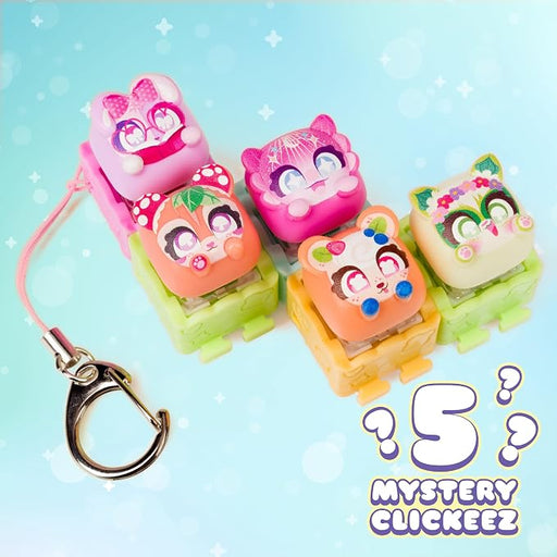 Five colorful cartoon-shaped plastic keychain clickers arranged on a light blue background with a metal key ring and the text '5 MYSTERY CLIQUEKEEZ'.