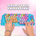 A hands-on promotional shot of a colorful toy keyboard with many small character-shaped keys. Two hands with turquoise nail polish are pressing the keys on a bright blue tray.