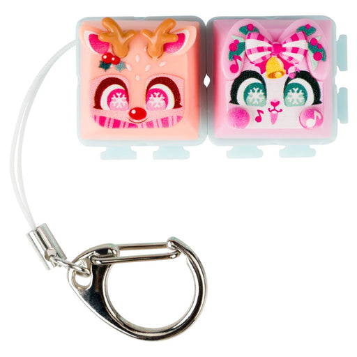 A pair of small square pink accessory cases with cartoon face designs, attached to a white cord and silver carabiner, on a white background.