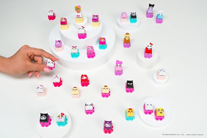 A hand holds a small colorful character toy while many similar character figures are arranged on white display stands against a clean white background.