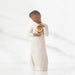 Figurine of a woman holding a gold heart against a white background