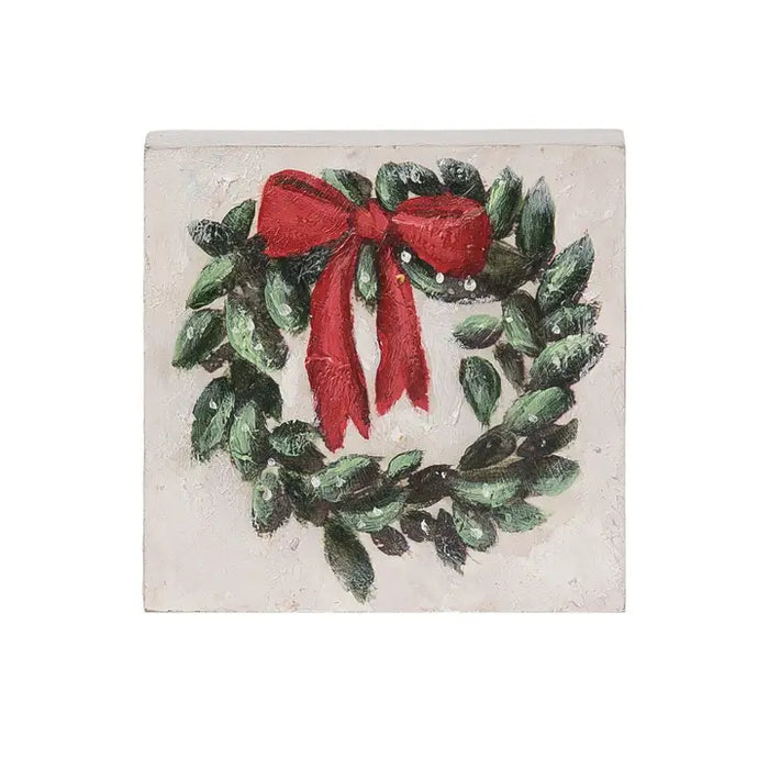 Decorative wall art with a green wreath and red bow on a textured beige background