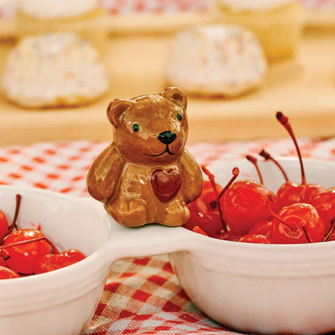 Bear-shaped cookie with a heart and cherries on a checkered tablecloth