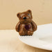 Brown ceramic bear with a red heart on a beige background