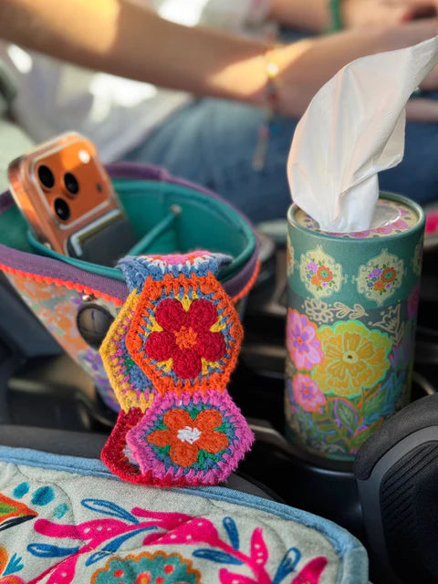 Colorful embroidered flower pattern on a car seat with a tissue holder and phone in the background.