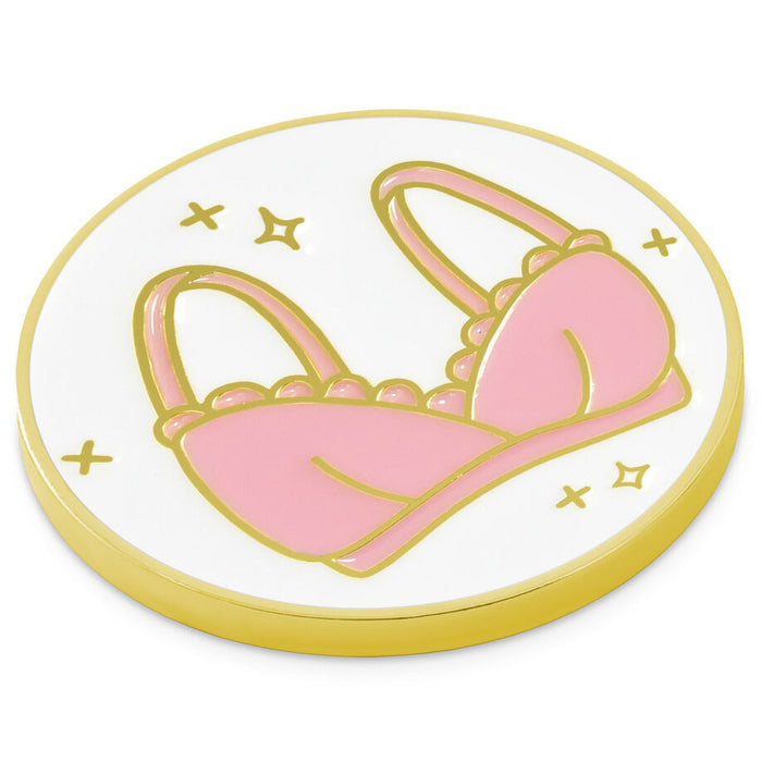 Pink bra design on a round white token with gold border and stars.