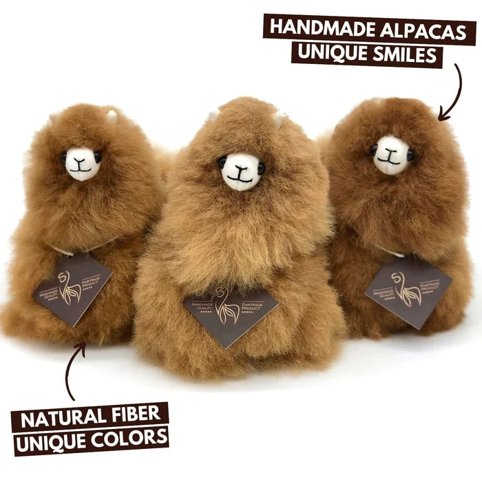 Three fluffy brown alpaca plush toys with white snouts and black eyes, shown on a white background with promotional text overlays reading 'HANDMADE ALPACAS UNIQUE SMILES' and 'NATURAL FIBER UNIQUE COLORS.'.