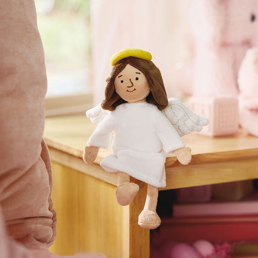 Plush angel toy sitting on a wooden surface with a blurred background