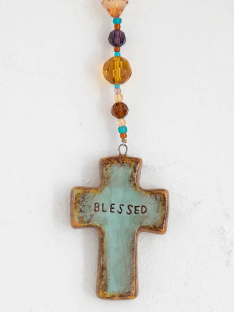 Cross-shaped pendant with 'Blessed' text and colorful beads on a white background