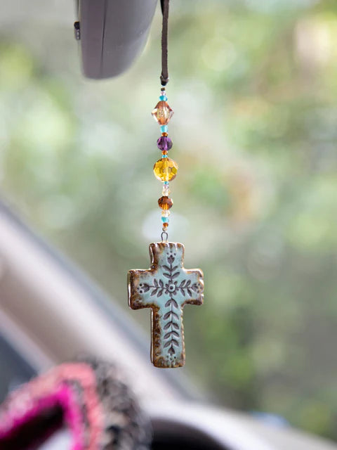 Decorative cross with beads hanging from a car's rearview mirror